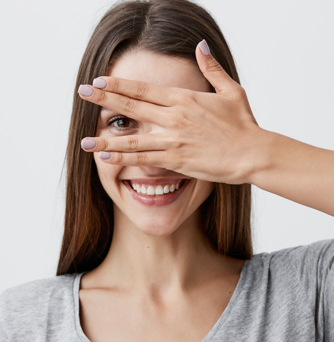 mujer joven sonriente tapándose un ojo con una mano