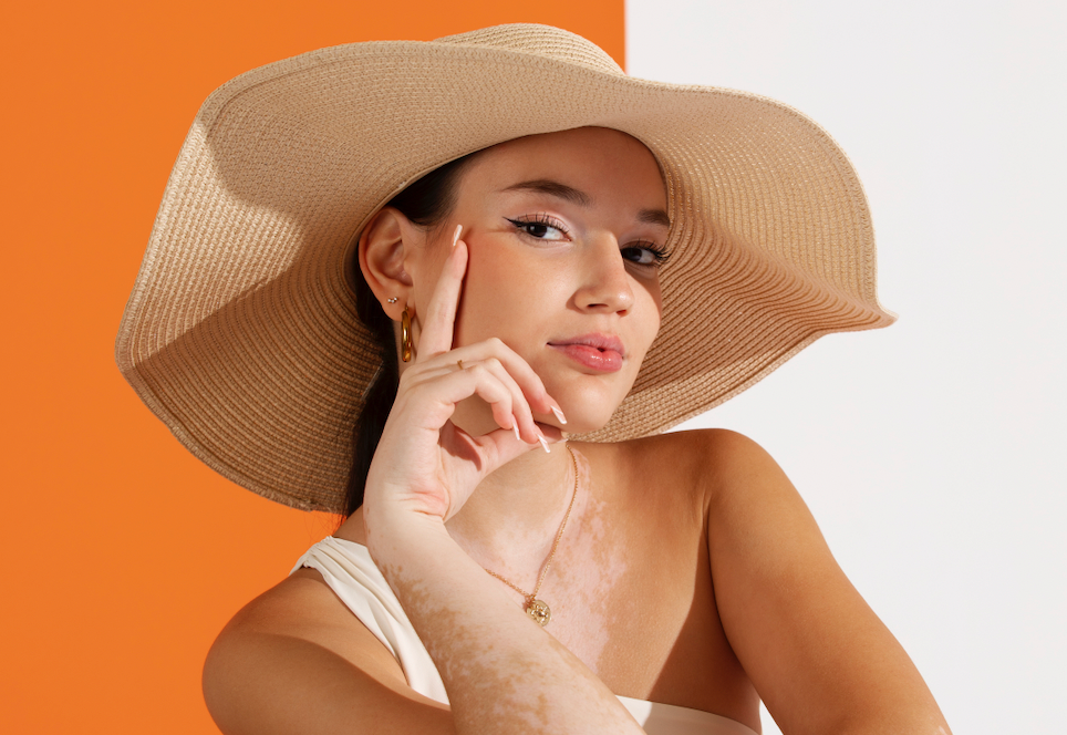 mujer piel perfecta en verano con gorro fondo naranja