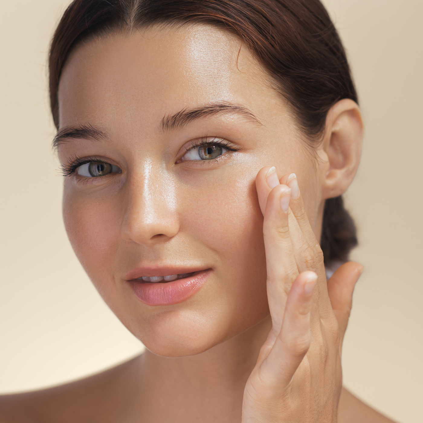 Mujer morena aplicándose crema facial con sonrisa satisfecha, piel cuidada e hidratada