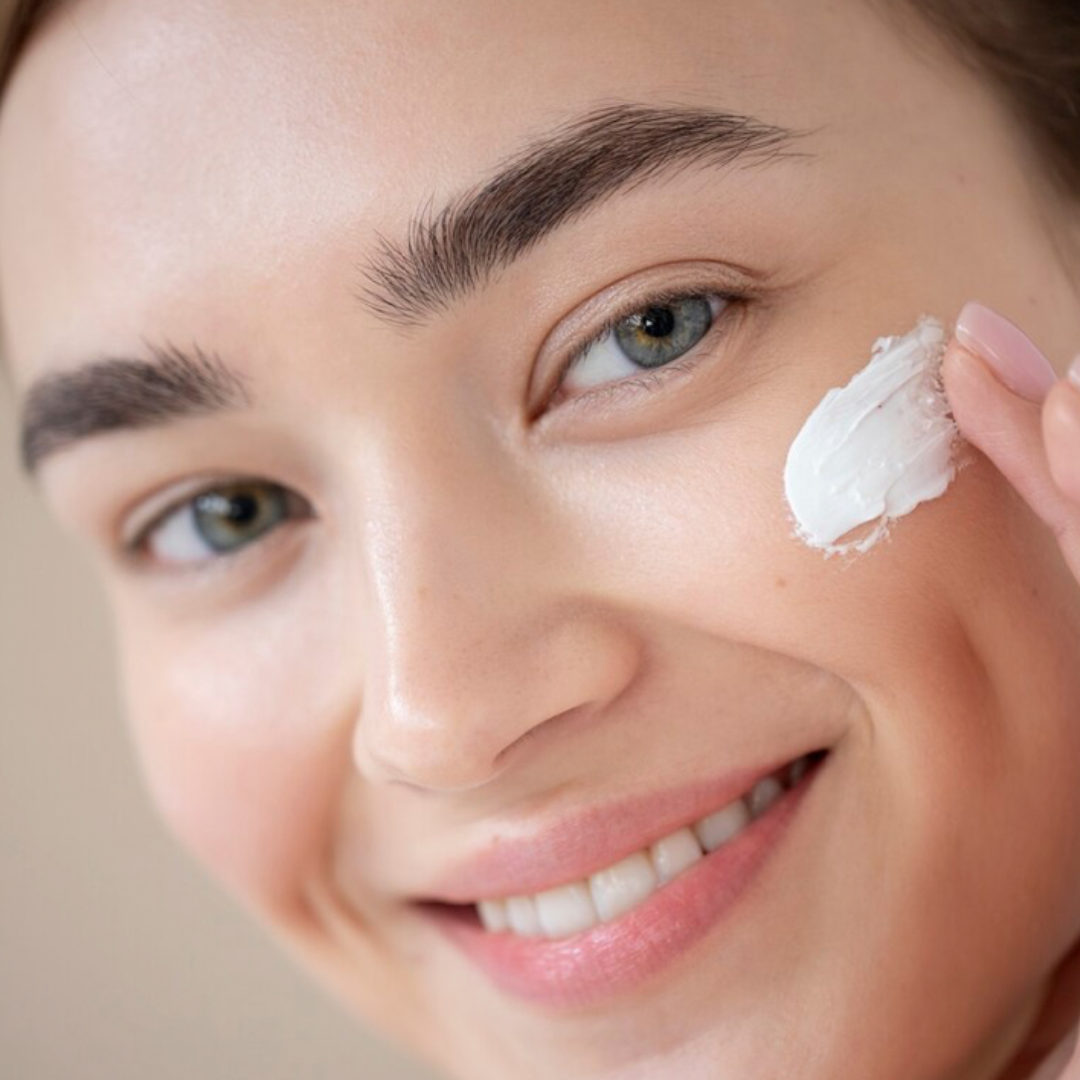 mujer sonriente echándose crema hidratante en la cara