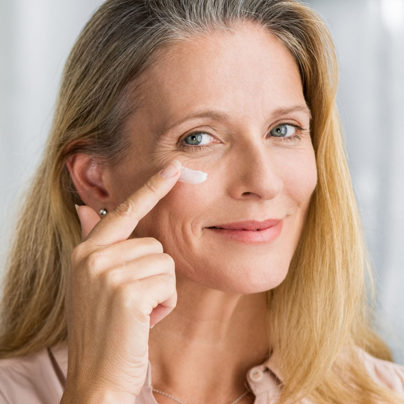 Mujer aplicando crema facial con gesto relajado, símbolo del cuidado antiedad natural con bakuchiol