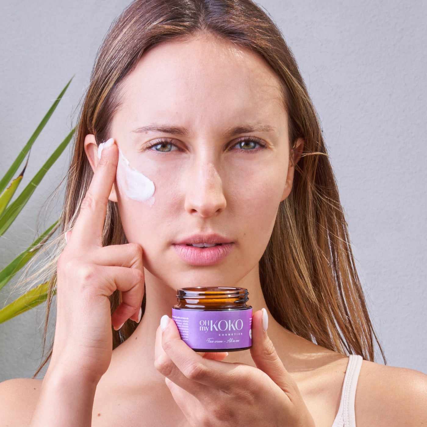 Mujer aplicándose una crema facial natural y vegana de OhMyKoko, ejemplo de cosmética limpia sin tóxicos.