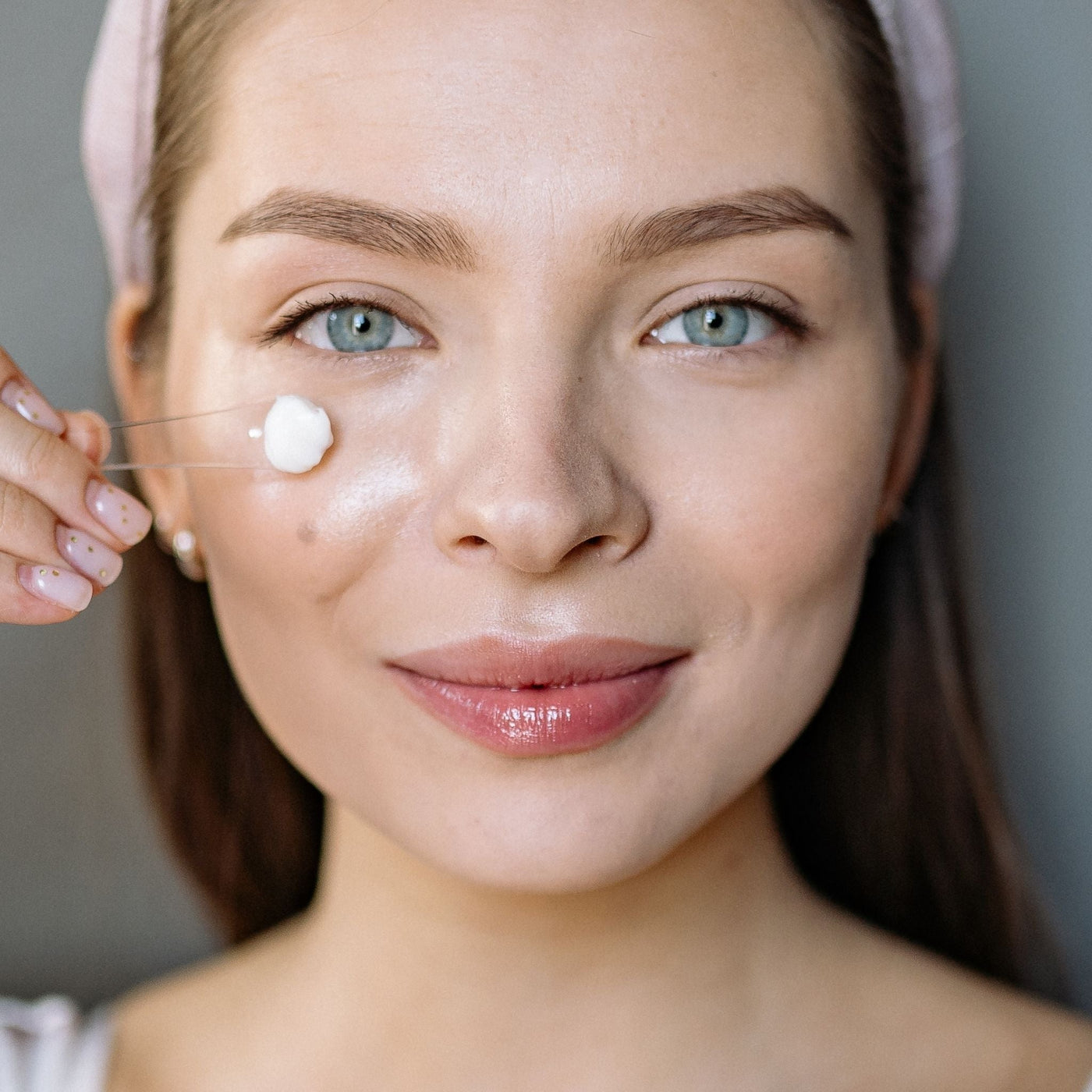 Mujer feliz aplicándose crema facial sin efecto borrador, sin grumos ni pelotillas, ideal para una piel hidratada y sin residuos.