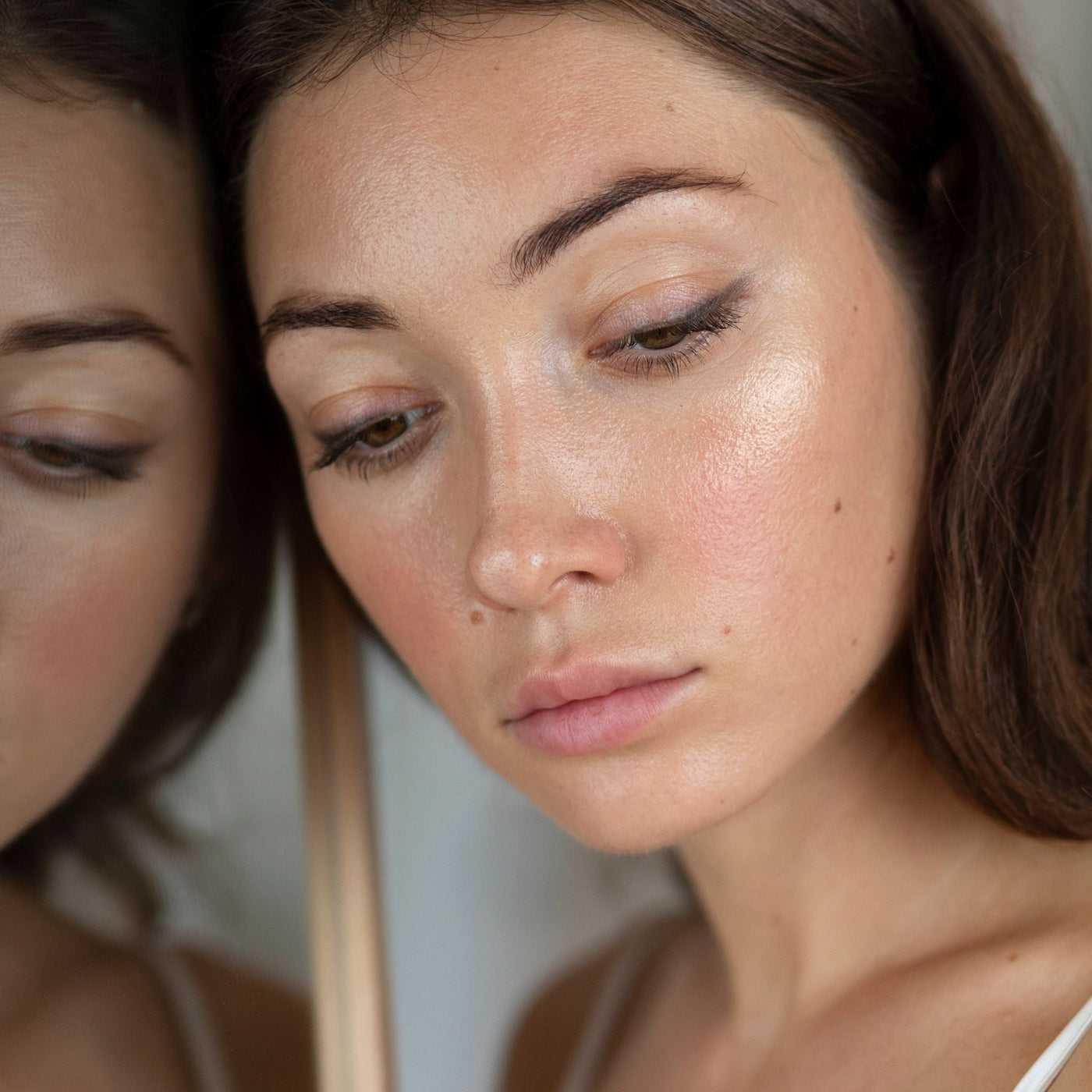 Mujer pensativa tocándose el rostro, reflejando los efectos del estrés en la piel.