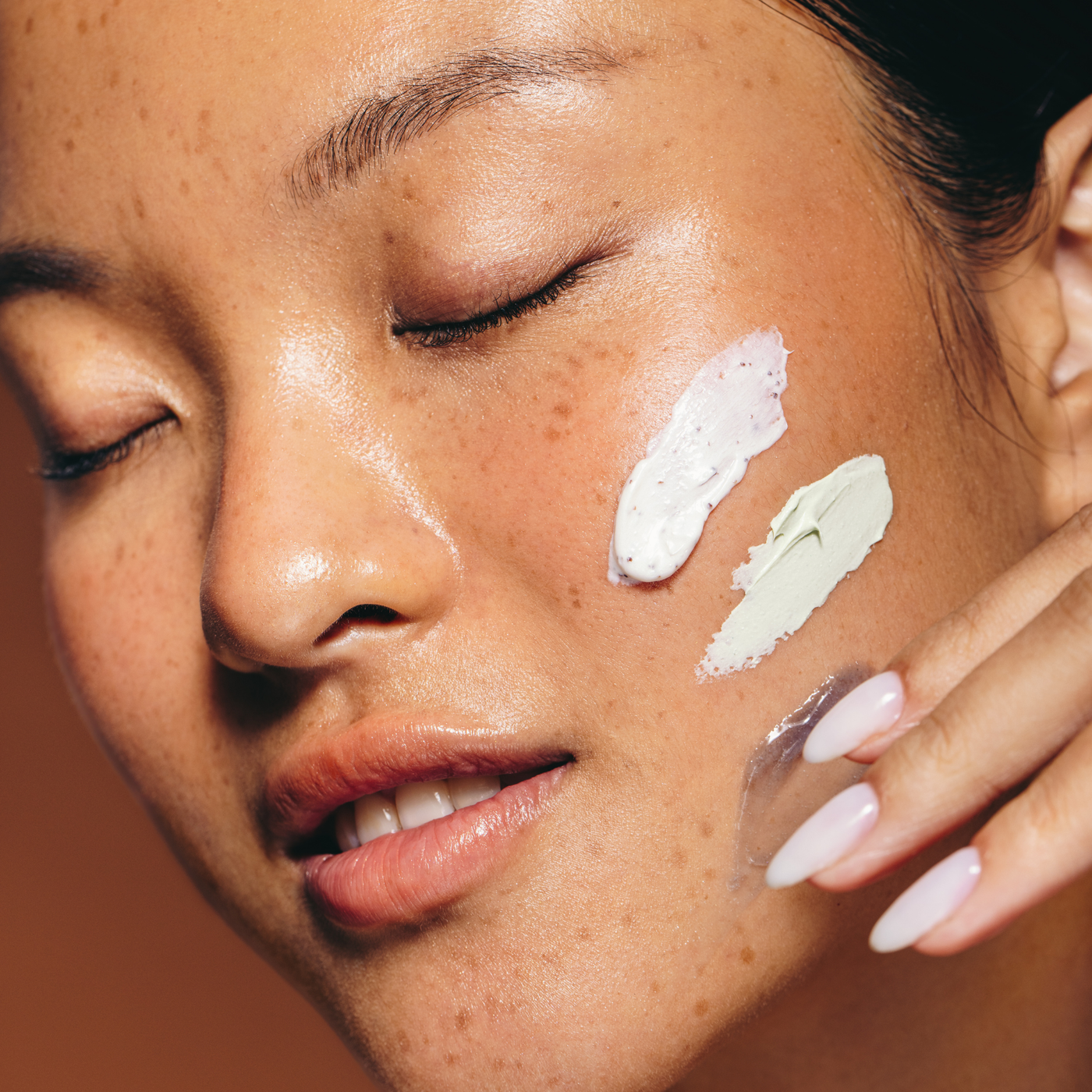 Mujer asiática aplicando crema hidratante en el rostro, cuidado de la piel seca