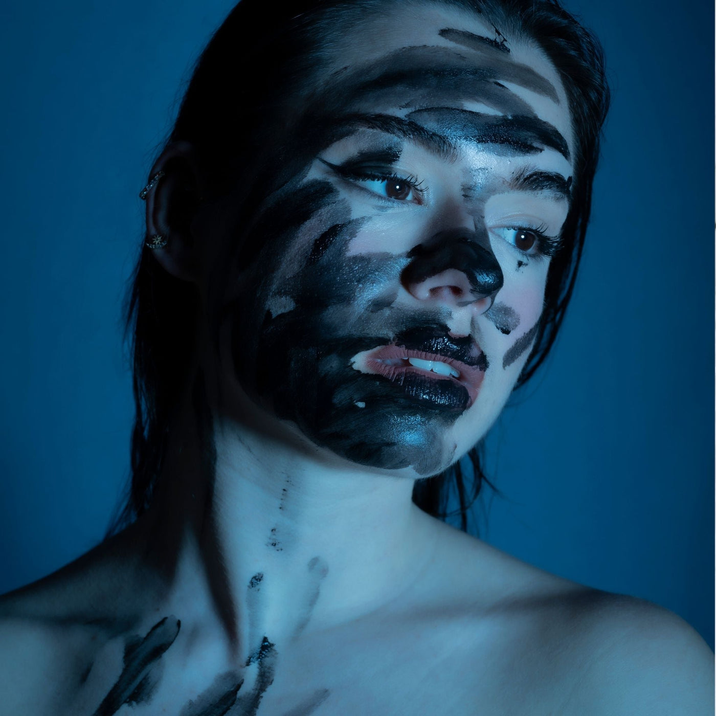 Helena Arauz con el rostro cubierto de negro en una imagen artística que representa los ingredientes tóxicos en cosmética convencional. Campaña activista de OhMyKoko por una cosmética sin químicos.