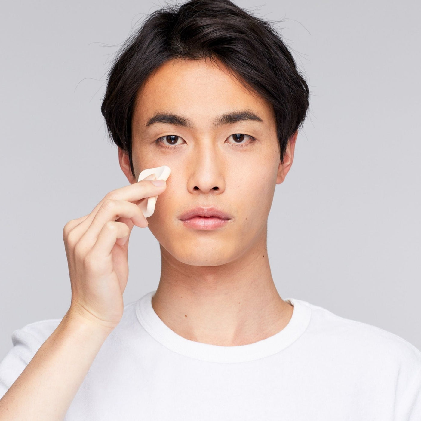 Hombre asiático realizando su rutina de cuidado facial con productos naturales OhMyKoko