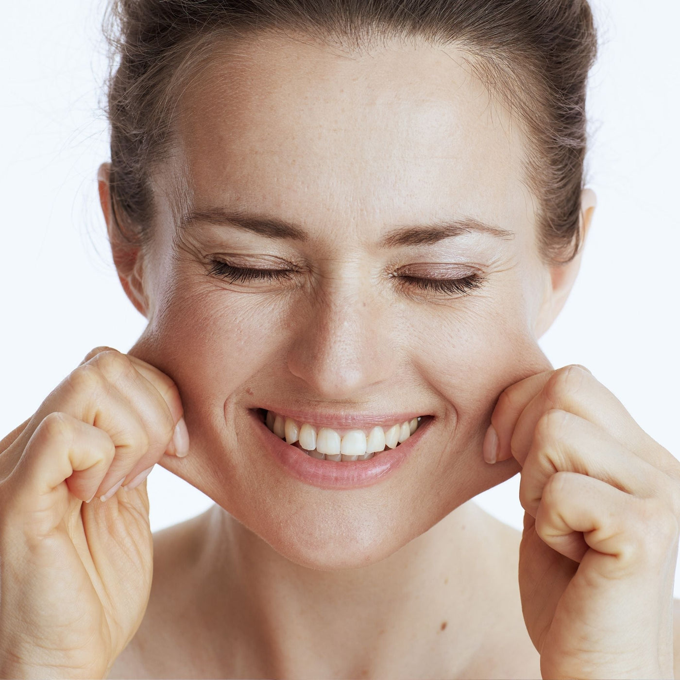 Mujer estirando suavemente las mejillas para mostrar flacidez y reafirmar el óvalo facial de forma natural