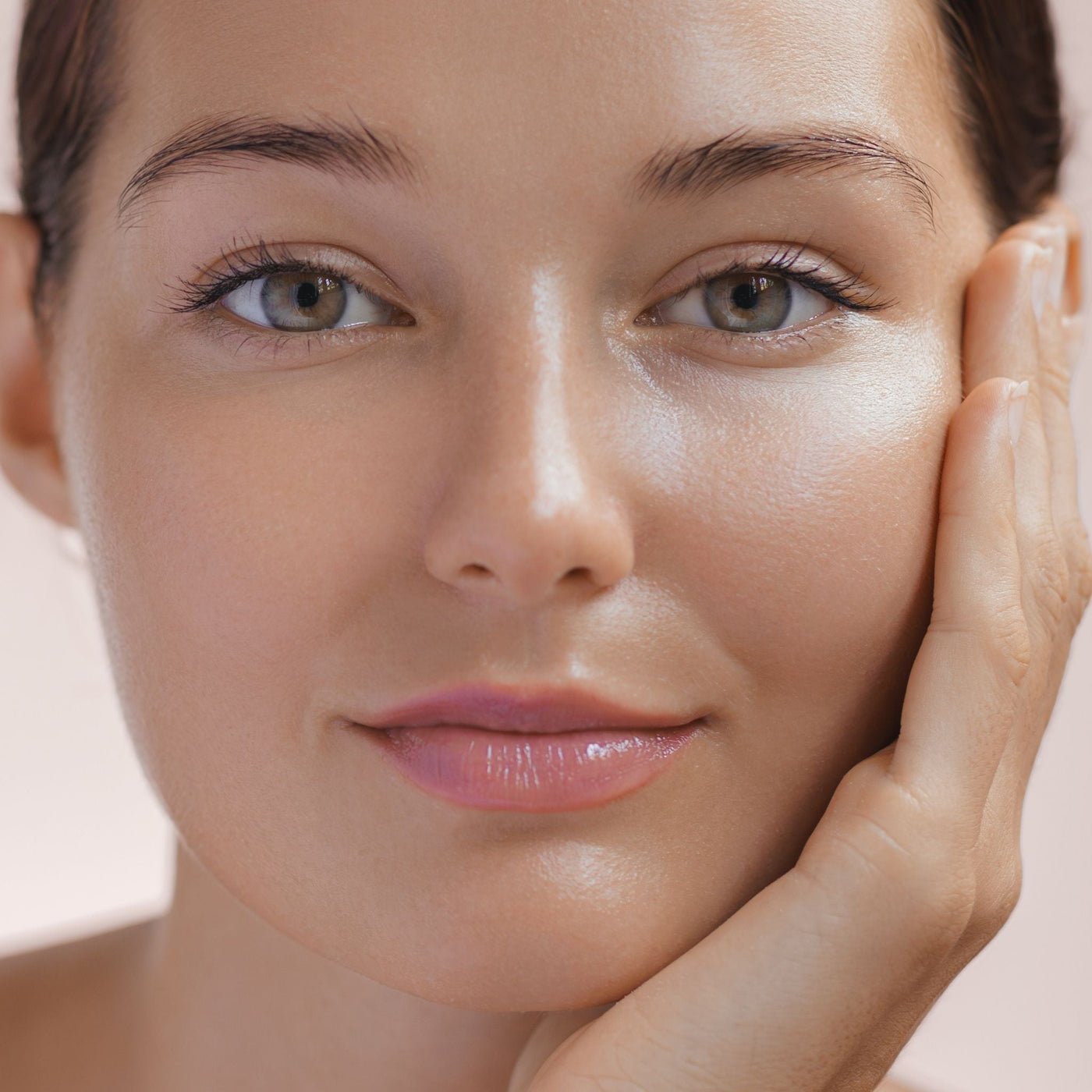 Persona con piel perfecta tocándose suavemente la cara, mostrando una piel sana y luminosa sin milium, cuidada con productos naturales OhMyKoko para prevenir y tratar los milium en el rostro.