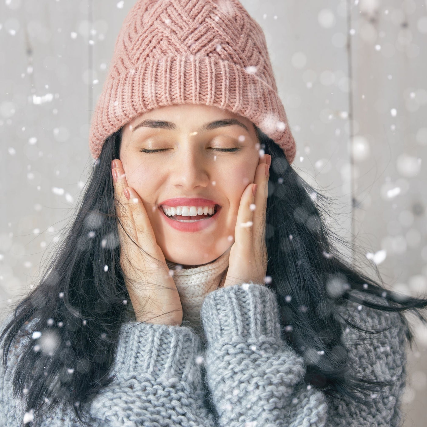 Chica con gorro de invierno tocándose la cara, representando los efectos del frío en la piel seca.
