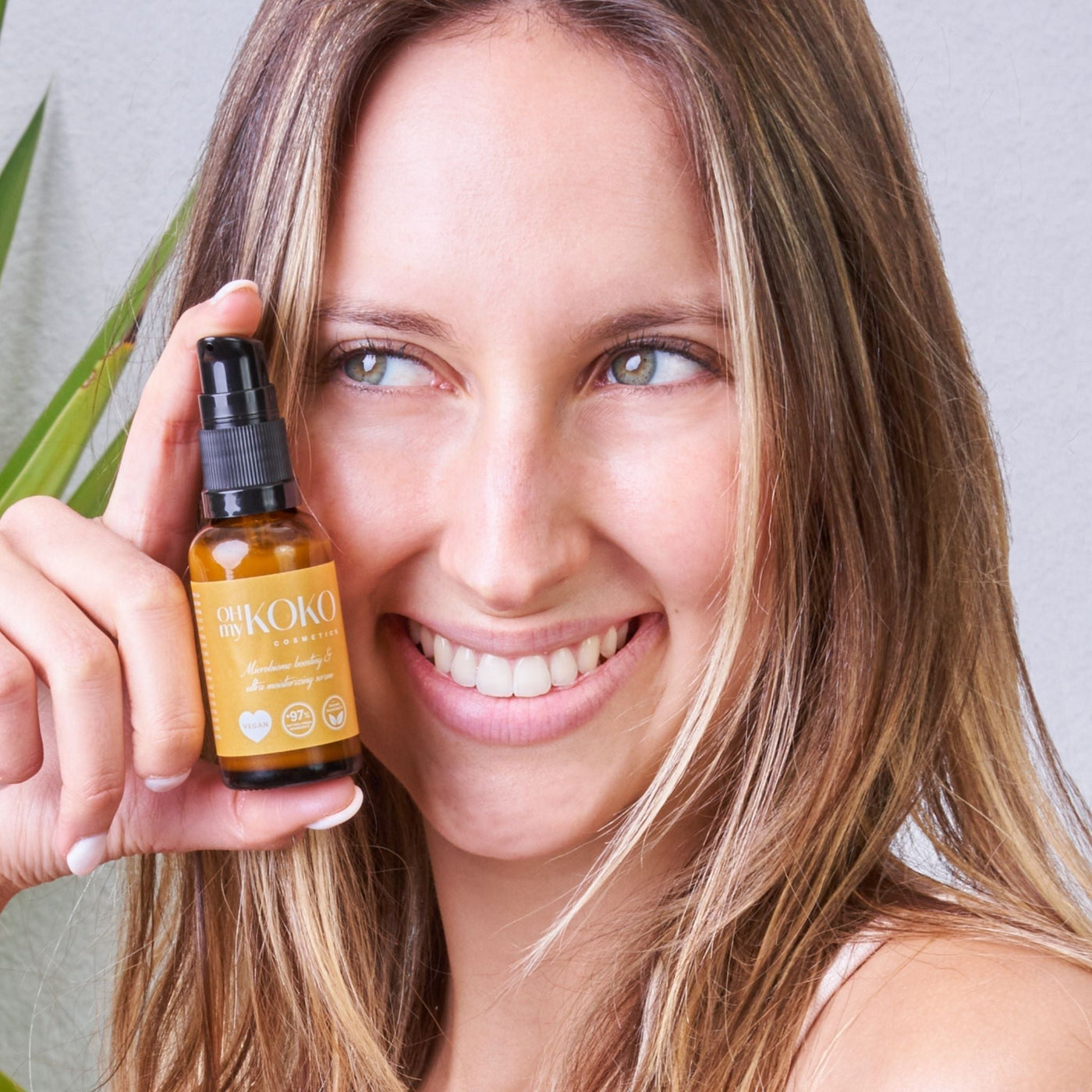 Mujer mostrando sérum facial ultrahidratante OhMyKoko con ácido hialurónico y probióticos veganos, ideal para piel seca y deshidratada, cuidando la barrera natural de la piel